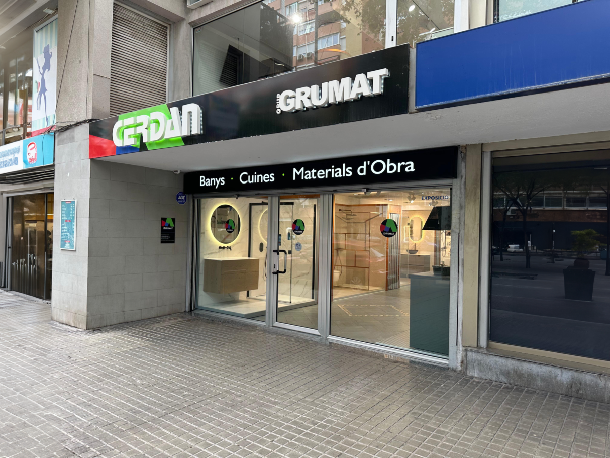 Fachada de una tienda de materiales de construcción con entradas de vidrio y cartel.