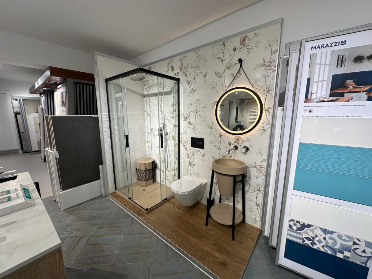 Baño moderno con ducha, inodoro y lavabo, decorado con papel pintado floral.