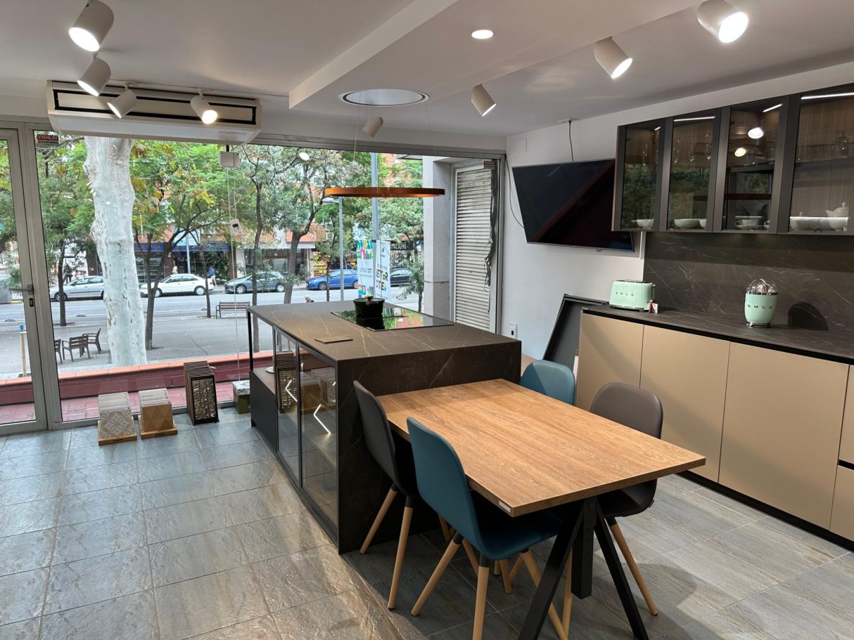 Cocina moderna con mesa de madera, sillas azules y ventanales al exterior.