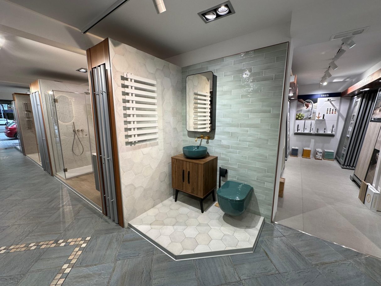 Baño moderno con lavabo de madera, espejos y paredes de azulejos claros.