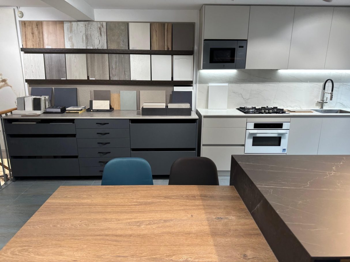 Cocina moderna con armarios, electrodomésticos y mesa de madera.